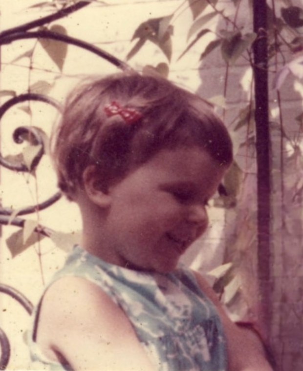 Caroline as a small child with a red bow in her hair, smiling